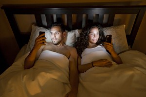 Sleep deprivation - couple using phones in bed